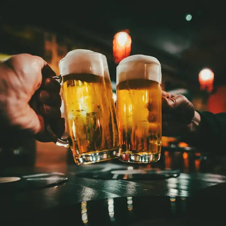 Två stora sejdelglas fyllda med skummande öl i Gdansk som skålas mot varandra i en stämningsfullt belyst bar.