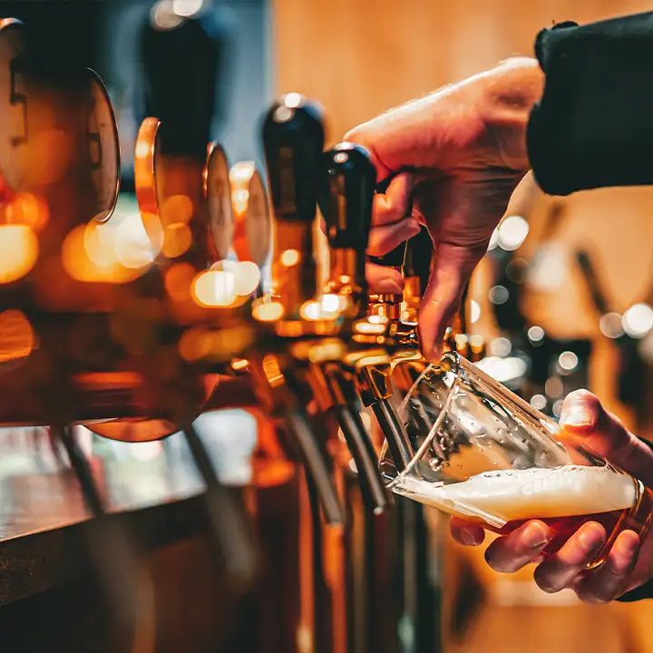En bartender tappar upp en kall hantverksbryggd öl i Gdansk från en av många kranar i en modern och stämningsfull bar.